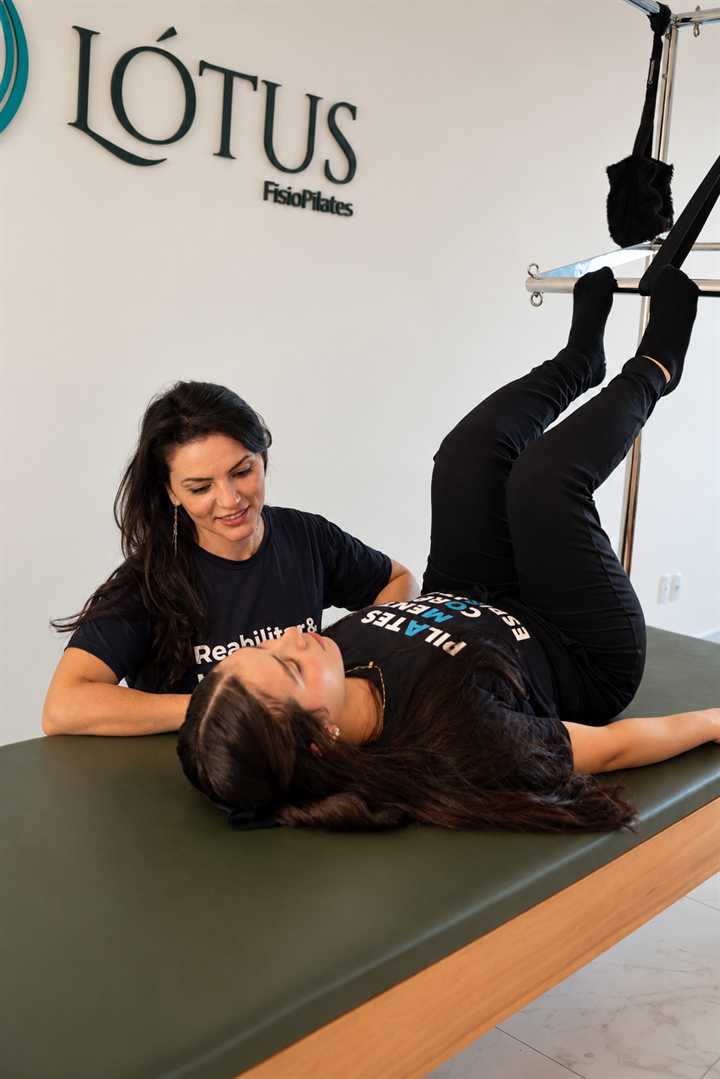 Profissional da Lótus FisioPilates acompanhando uma pessoa no reformer